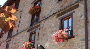 A stone building with multiple windows, some with flower boxes. - La Cuculla (Ezcaray)