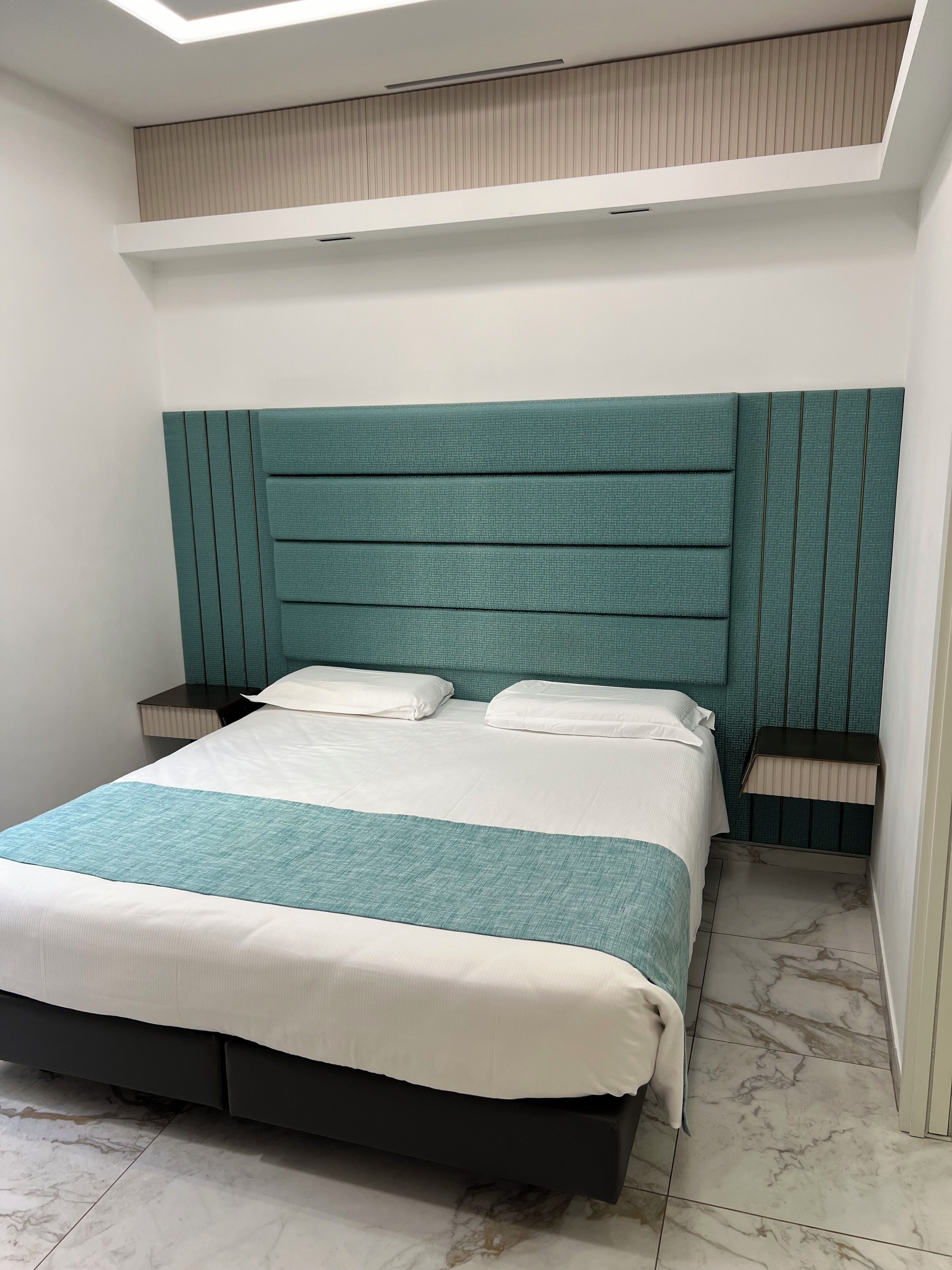 A bedroom with a bed, nightstands, a headboard, and a skylight.