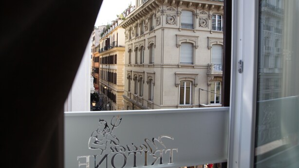 Vista de un edificio con detalles arquitectónicos ornamentales y un balcón con un letrero.