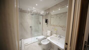 A modern bathroom with a glass-enclosed shower, a bidet, a sink, and a large mirror.