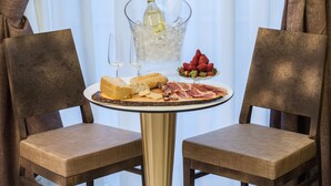 Una mesa con una botella de champán, copas, un plato de queso, pan y fresas.