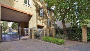 A brick building with a gated entrance, a sign reading "BRIAN COURT," and a tree in the foreground. - Austin David Apartments - Classic 2 Bed (London)