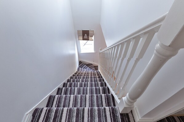 Un escalier avec une moquette à rayures et des rampes blanches.
