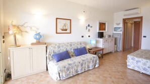 Una habitación con sofá, cama, escritorio, armario, televisor y microondas.