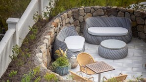 A patio with wicker furniture, stone walls, and potted plants. - Havgrím Seaside Hotel 1948 (Tórshavn)