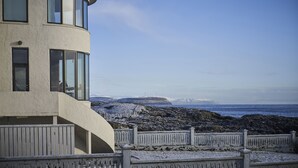 A coastal building with large windows, a curved facade, and a view of the sea and distant mountains. - Havgrím Seaside Hotel 1948 (Tórshavn)