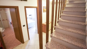 Eine Treppe mit Holzhandläufen und Blick auf ein Schlafzimmer mit Bett und Nachttisch.