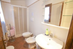 A bathroom with a toilet, bidet, sink, and mirror.