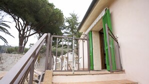 Un escalier avec une rampe en métal menant à une porte dotée de volets verts.