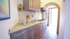 Une cuisine avec des meubles en bois, un pare-feu en carrelage et une cuisinière à gaz.