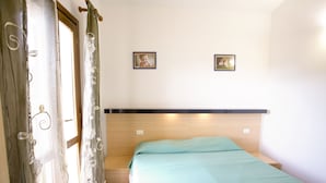 Une chambre à coucher avec un lit, des rideaux et deux tableaux encadrés accrochés au mur.
