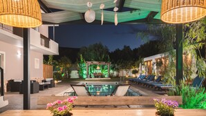 A poolside area with lounge chairs, a wooden bench, and potted plants. - Bruma Luxury Residence (Zakynthos)