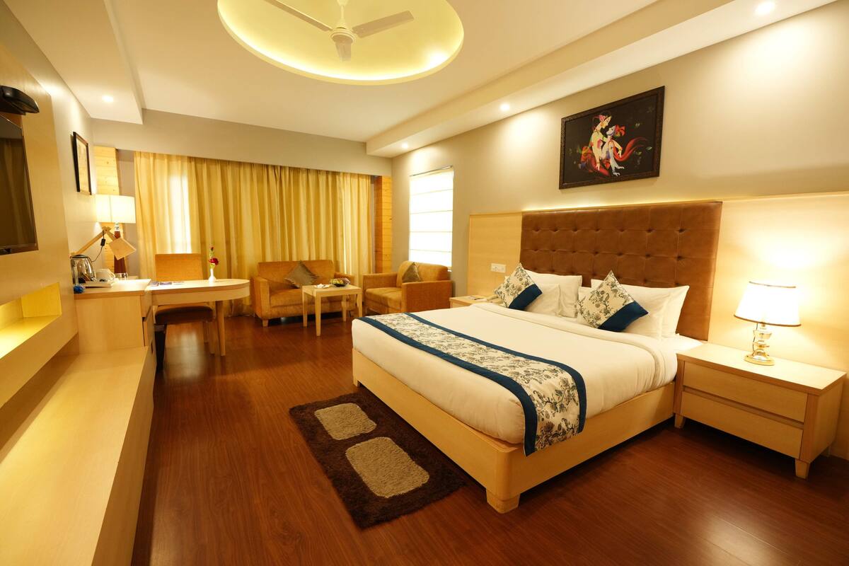 A hotel room with a large bed, a desk, a chair, and a TV.