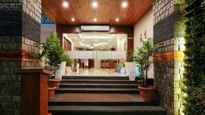 Een hotel lobby met een houten plafond, stenen muren en een centrale trap naar een hoger gelegen verdieping.