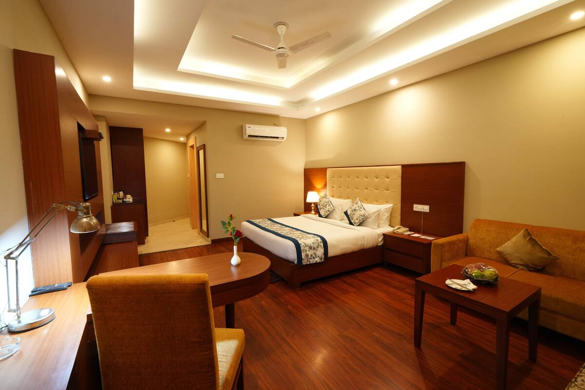 A hotel room with a bed, a sofa, a desk, and a chair.