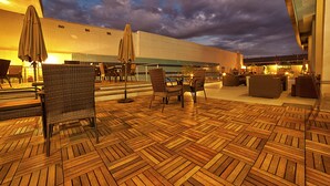 An outdoor patio area with wooden flooring, wicker chairs, and umbrellas. - New Hotel - Nampula (Nampula)