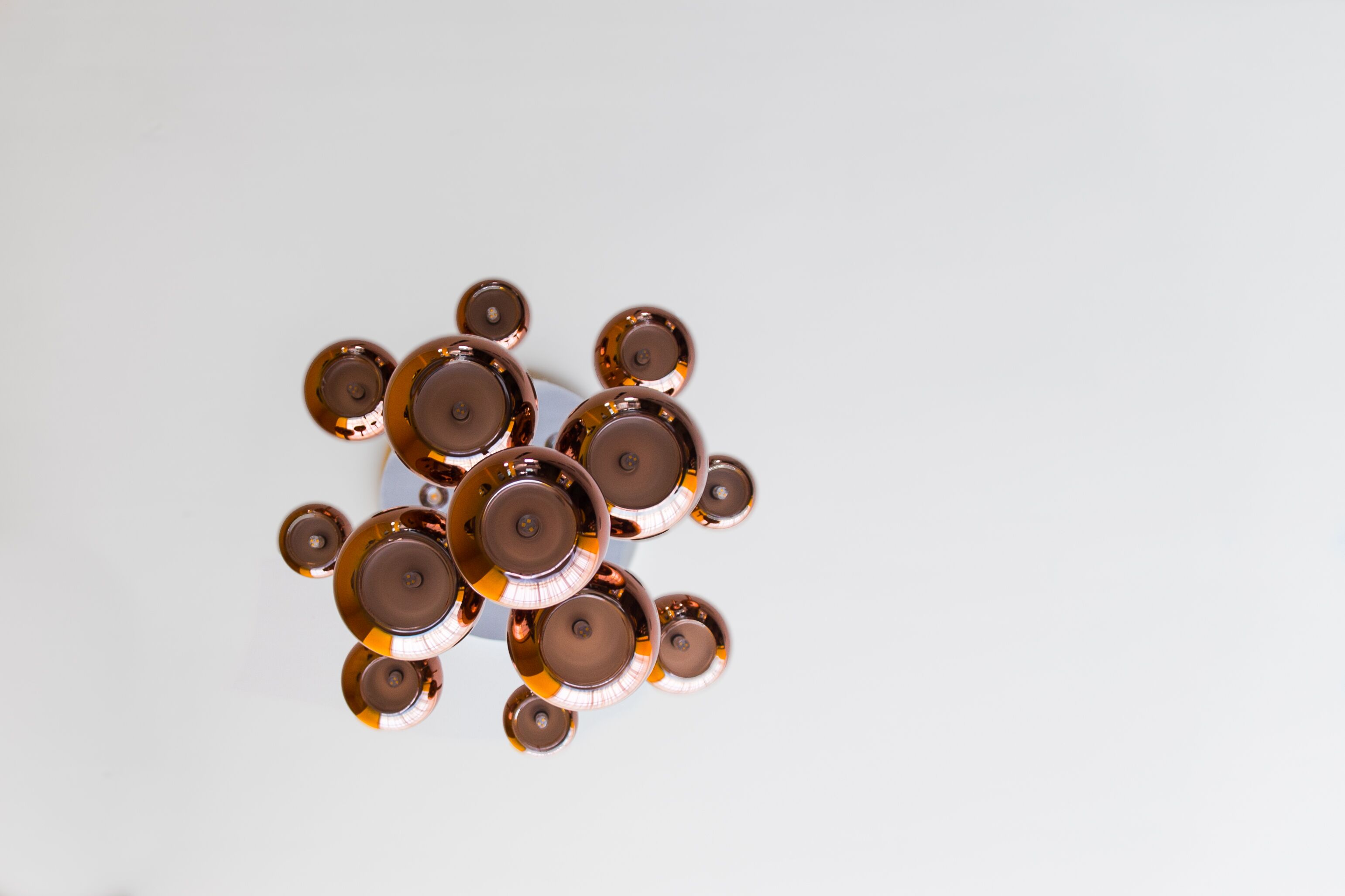 A cluster of metallic, circular objects with a reflective surface, arranged closely together on a plain background.