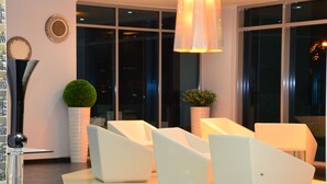A modern hotel lobby with white furniture, large windows, and decorative elements like a potted plant and wall art. - New Hotel - Nampula (Nampula)