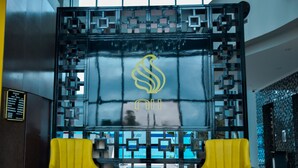 A modern lobby with a glass partition displaying a logo, two yellow armchairs, and a reception desk. - New Hotel - Nampula (Nampula)