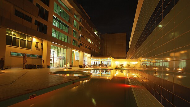 A modern building with a reflective pool and illuminated windows at night. - New Hotel - Nampula (Nampula)