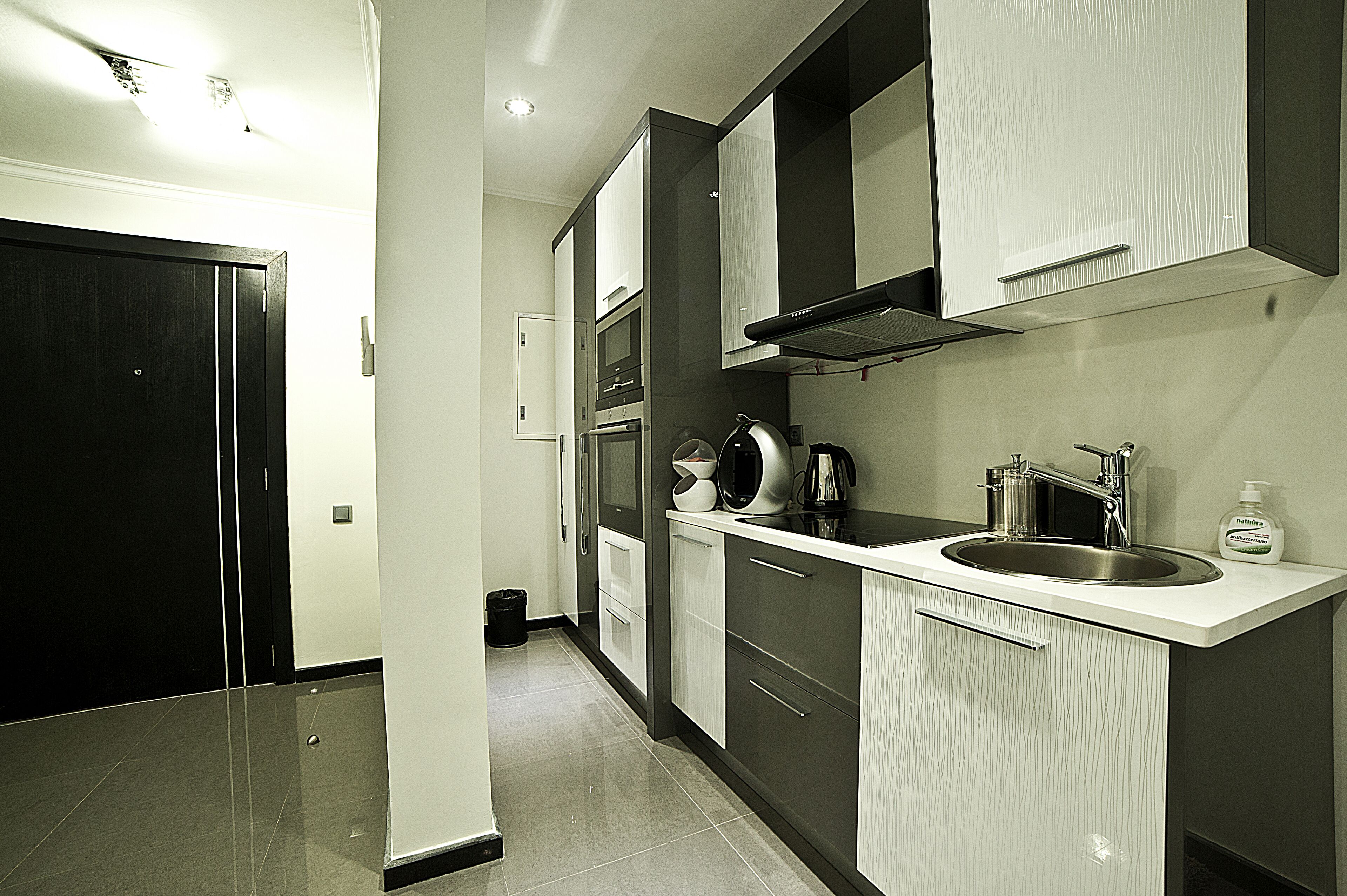 A modern kitchen with a stainless steel sink, a microwave, and a kettle.