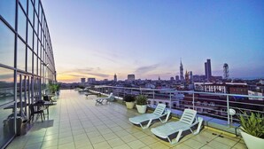 A rooftop terrace with lounge chairs, potted plants, and a city skyline view. - Mardi Plaza Hotel (Batumi)
