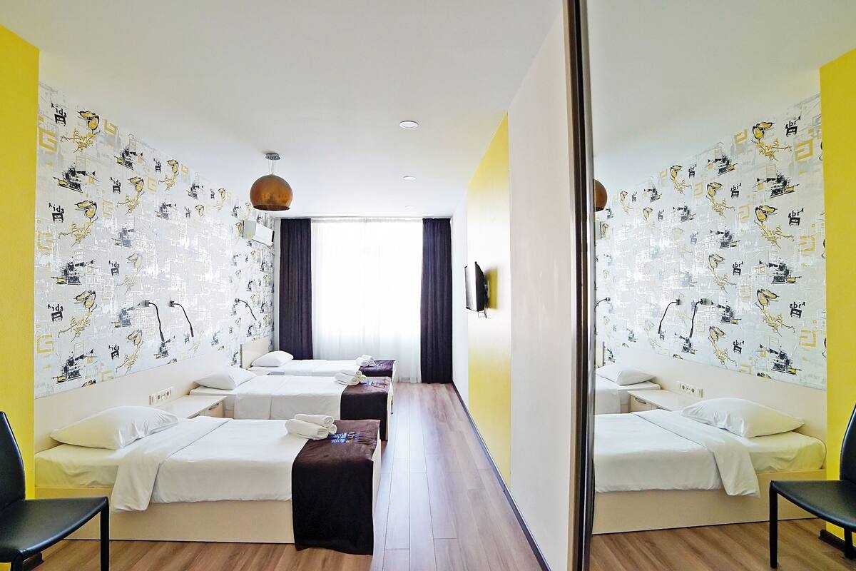A hotel room with two beds, a desk, and a mirror.