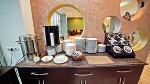 A buffet setup with stacked plates, bowls, and a coffee station. - Mardi Plaza Hotel (Batumi)