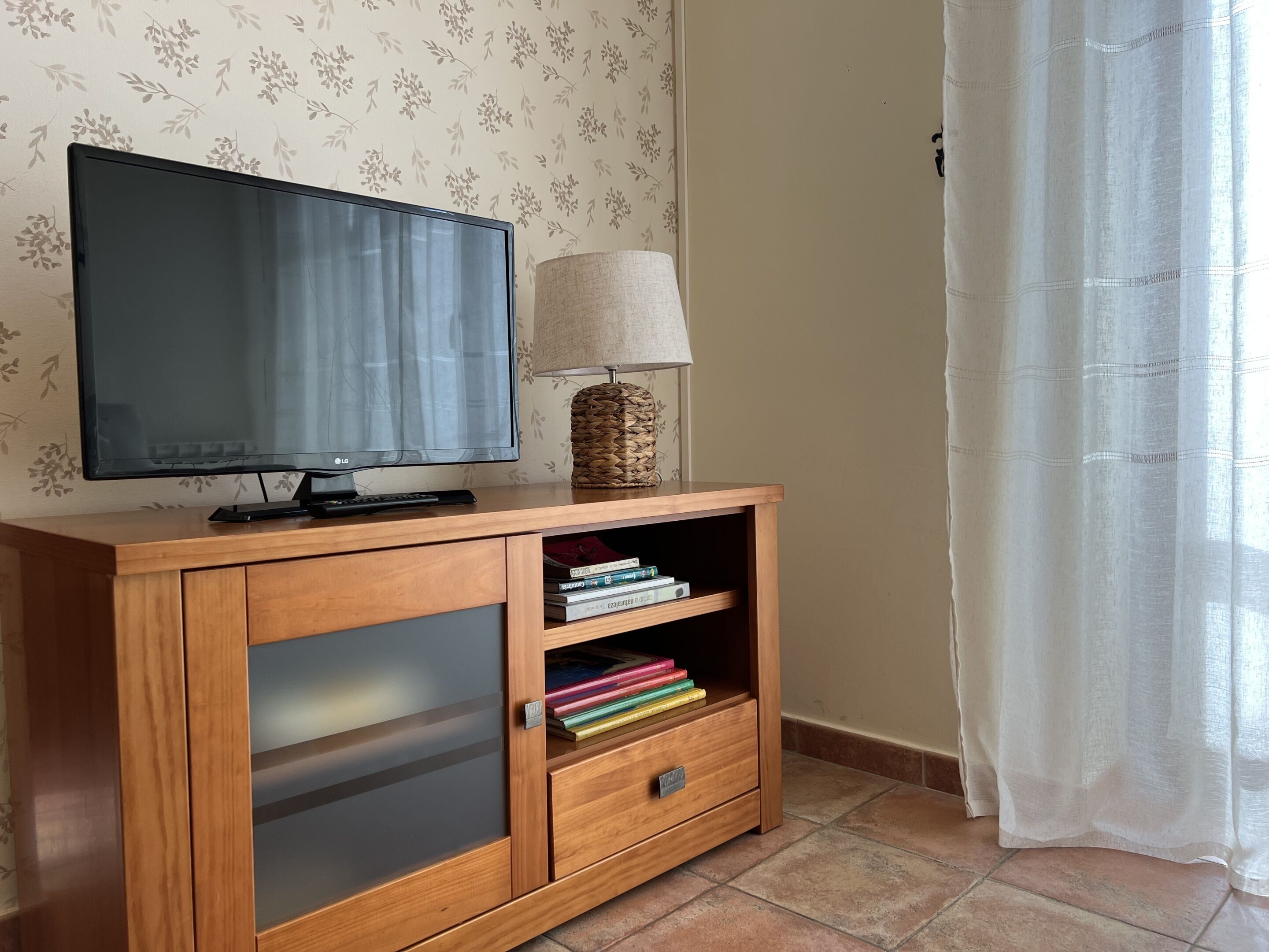 Un meuble en bois pour la télévision, avec un téléviseur à écran plat, une lampe et une étagère remplie de livres.