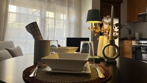 A dining area with a table set for two, a lamp, a vase with dried flowers, and a kitchen in the background. - Las Casucas de Remoña (Camaleno)