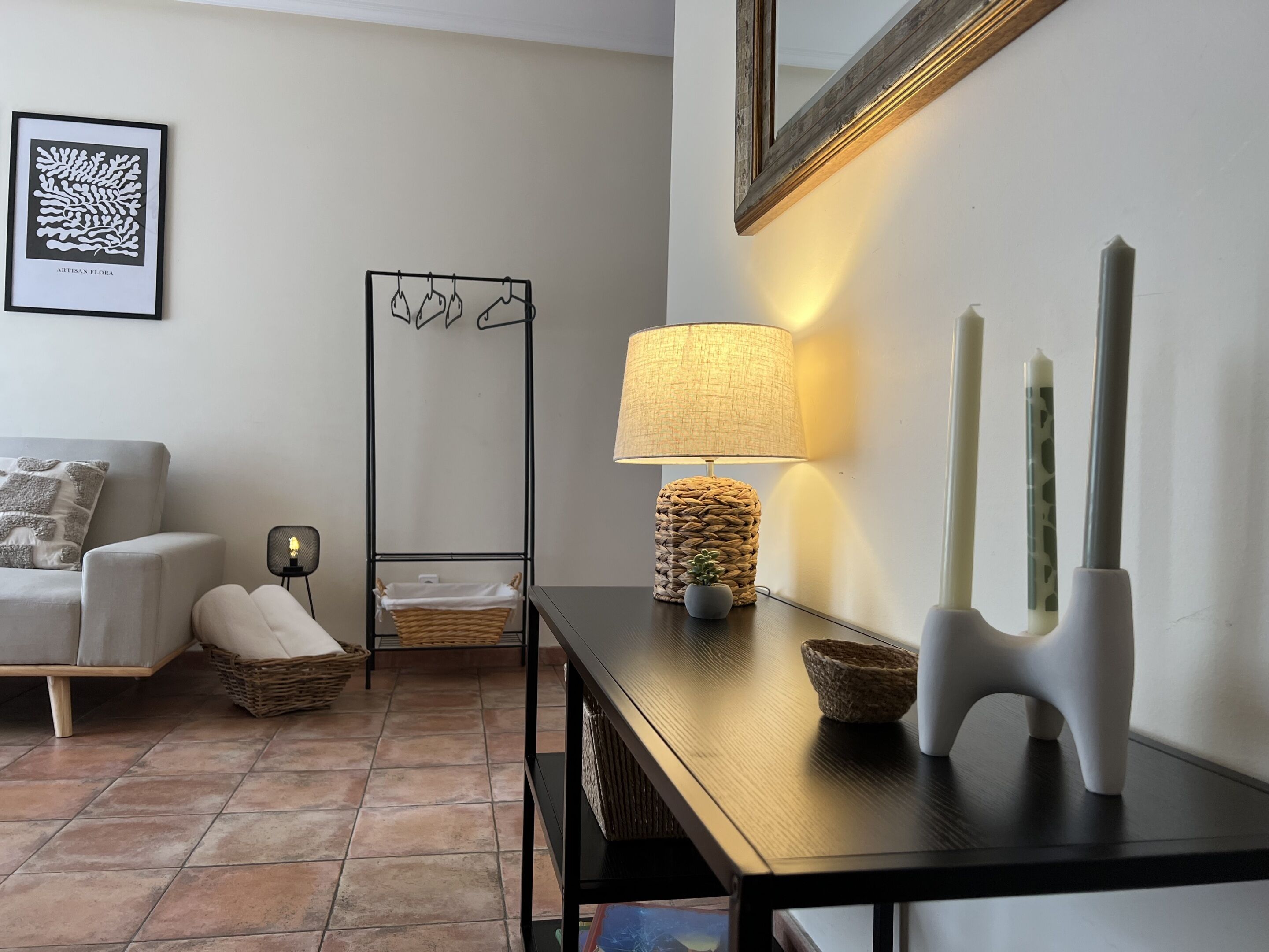 Sala de estar com sofá, luminária, espelho e uma obra de arte emoldurada na parede.