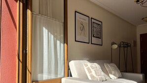 A room with a grey sofa, a wooden floor, a glass door, and two framed artworks on the wall. - Las Casucas de Remoña (Camaleno)