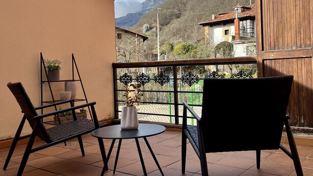 A balcony with two chairs, a small table, and a potted plant. - Las Casucas de Remoña (Camaleno)