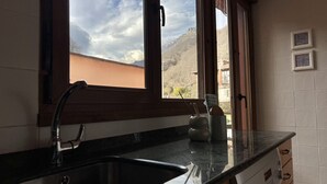 A kitchen with a large window, a sink, and a countertop. - Las Casucas de Remoña (Camaleno)