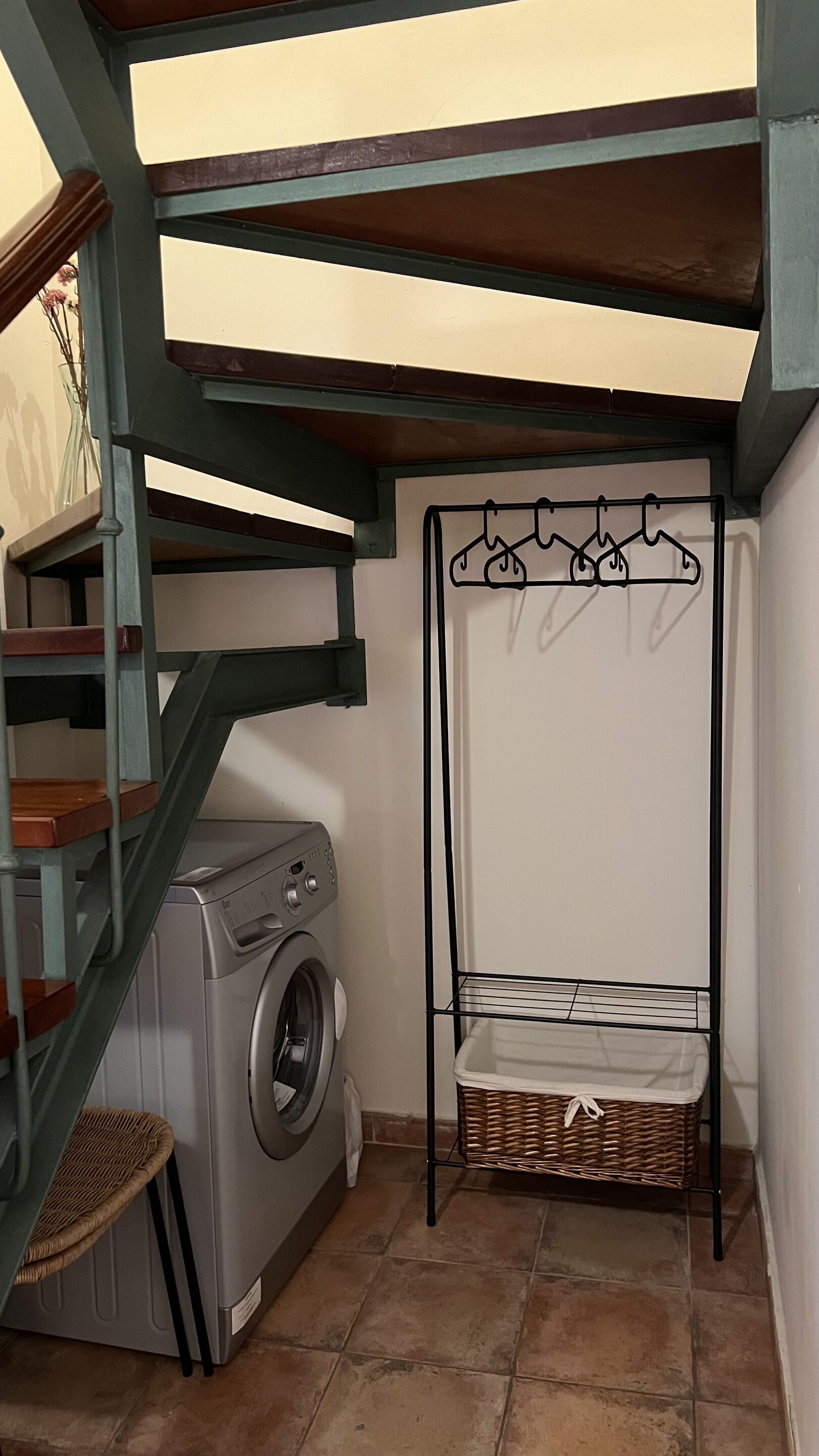 A laundry area with a washing machine, a drying rack, and a wicker basket.