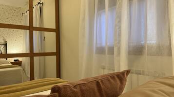 Un dormitorio con cama, mesita de noche, espejo y cortinas de encaje.