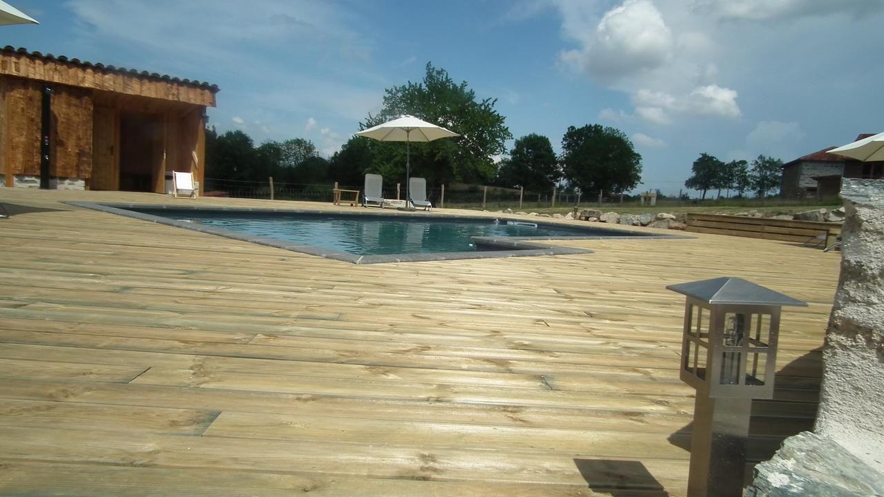 Eine Holzterrasse mit Schwimmbecken, Liegestühlen und Sonnenschirmen.