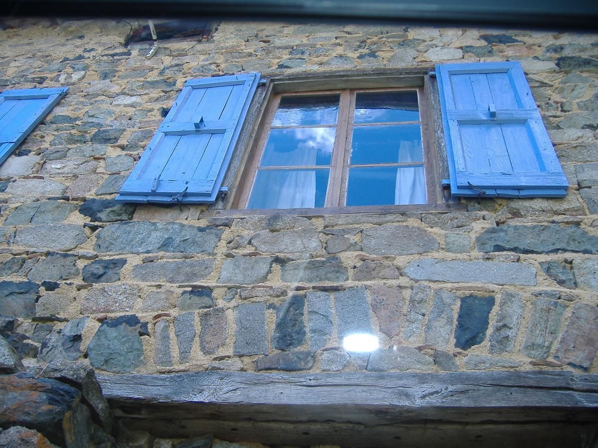 A stone building with a window and wooden shutters.