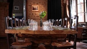 A rustic dining room with a long wooden table set for a meal, flanked by wooden chairs.