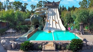 Parque acuático con un tobogán grande y una piscina.