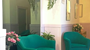 Una habitación con sofás azul verdosos, una planta en maceta y un jarrón con flores.