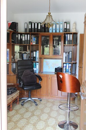 A home office with a desk, chair, bookshelf, and a map on the wall. - Costas Hostel Action (Tseri)