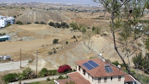 A building with a solar panel on the roof, surrounded by a hilly landscape and sparse vegetation. - Costas Hostel Action (Tseri)