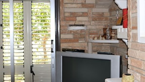 A room with a brick wall, a television, and a door with blinds. - Costas Hostel Action (Tseri)