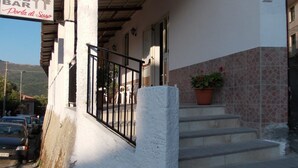 A building with a sign for a restaurant and bar, outdoor seating, and a staircase leading to the entrance. - B&B Porta di Suso (Camerota)