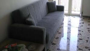 A living room with a grey sofa, a wooden coffee table, and a tiled floor. - B&B Porta di Suso (Camerota)