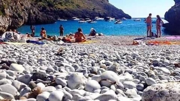 A pebble beach with people sunbathing and boats in the water. - B&B Porta di Suso (Camerota)