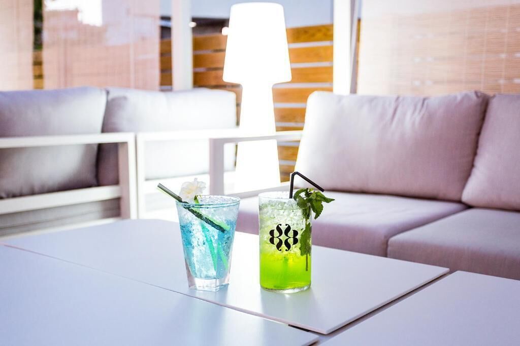 Un espace de détente moderne avec une table blanche, deux boissons et un canapé.