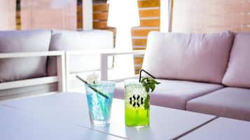 Un espace de détente moderne avec une table blanche, deux boissons et un canapé.