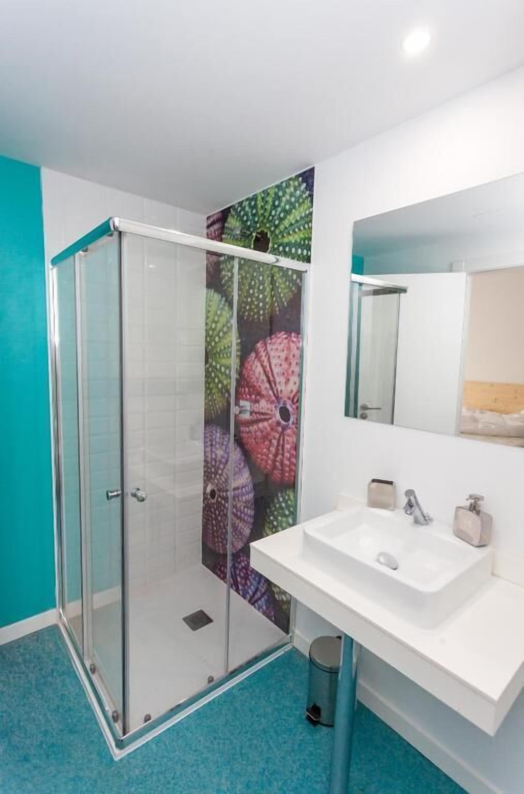 A bathroom with a glass shower enclosure, a white sink, and a mirror above it.